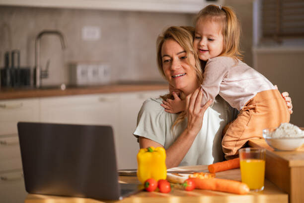 Blije moeder en haar dochter gebruiken de laptop en eten gezond