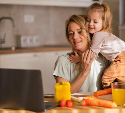 Blije moeder en haar dochter gebruiken de laptop en eten gezond